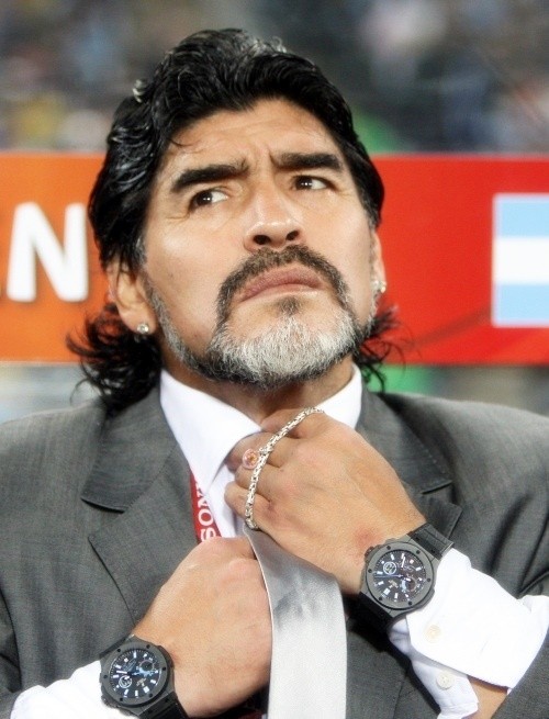 Diego Maradona adjusting his necktie wearing a suit picked by his daughters